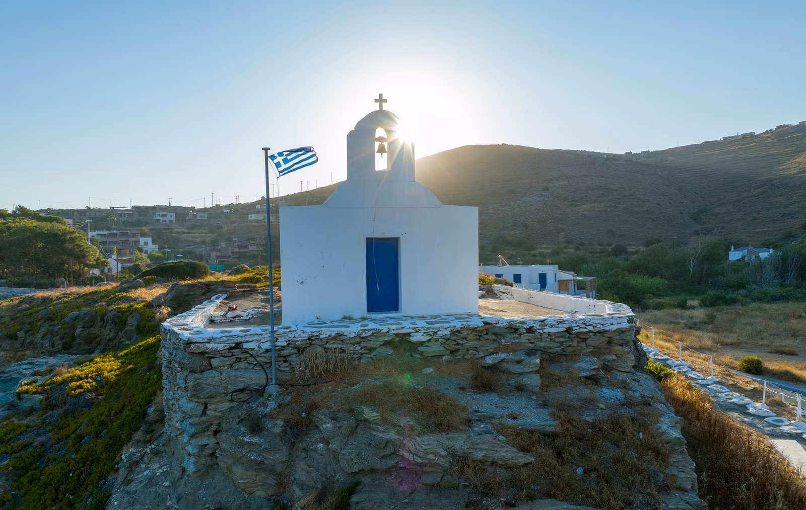 A whitewashed chapel on a rocky point above Kea, from a drone