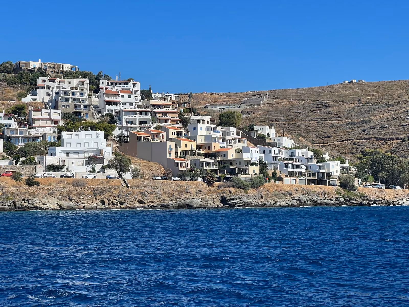 Whitewashed houses climbing a dry Cycladic hillside