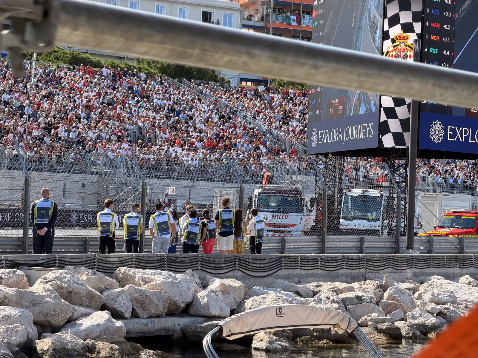 A packed grandstand above the track and the marshals' line