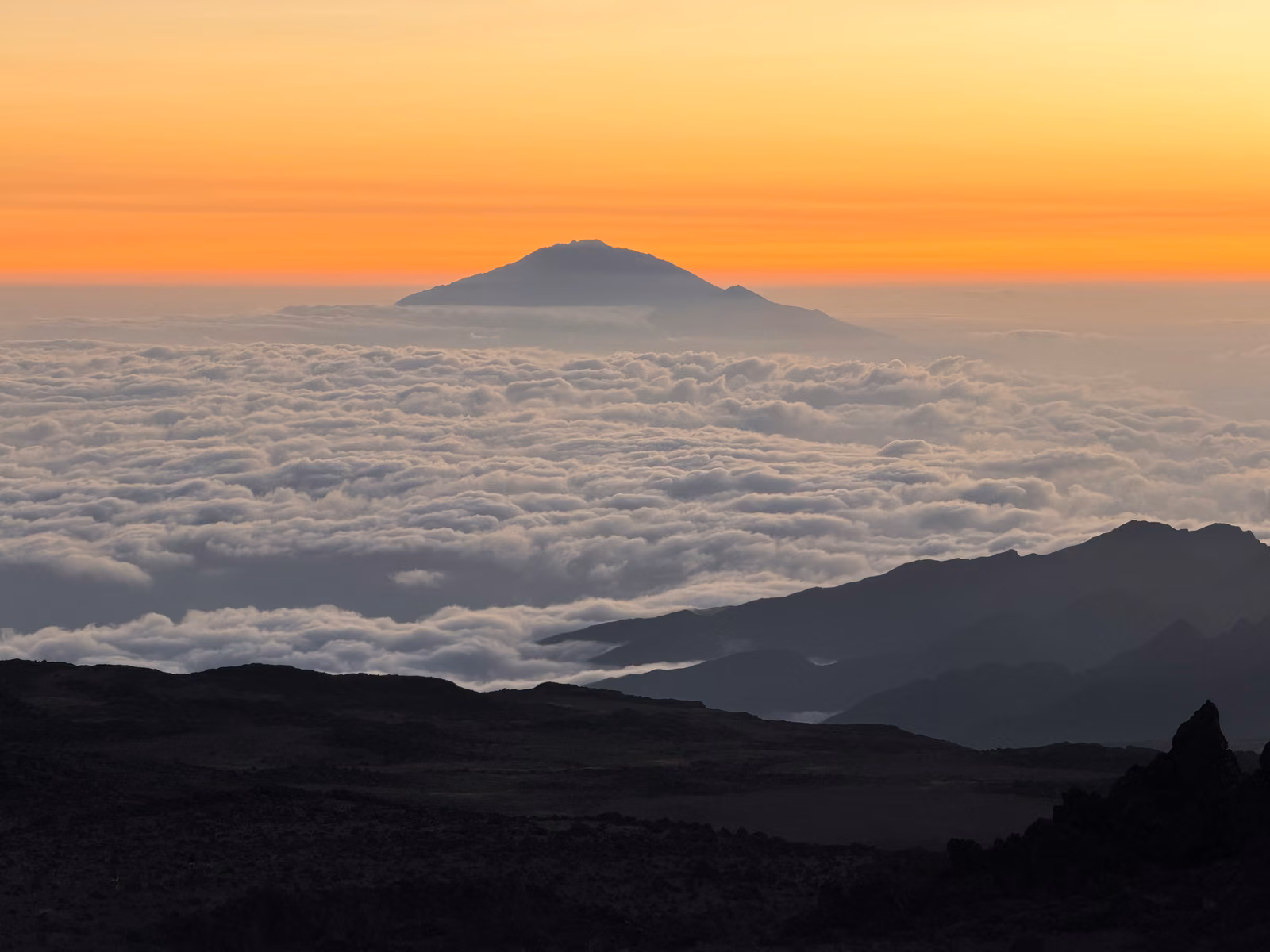 Mount Meru rising above a sea of cloud at sunset