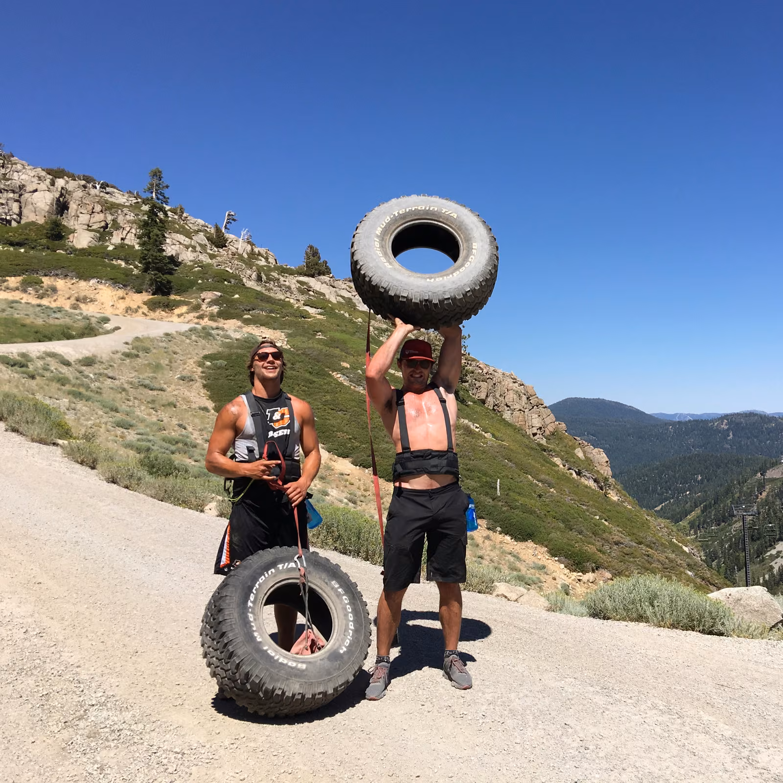 A man lifting a tire overhead above Lake Tahoe, expedition training