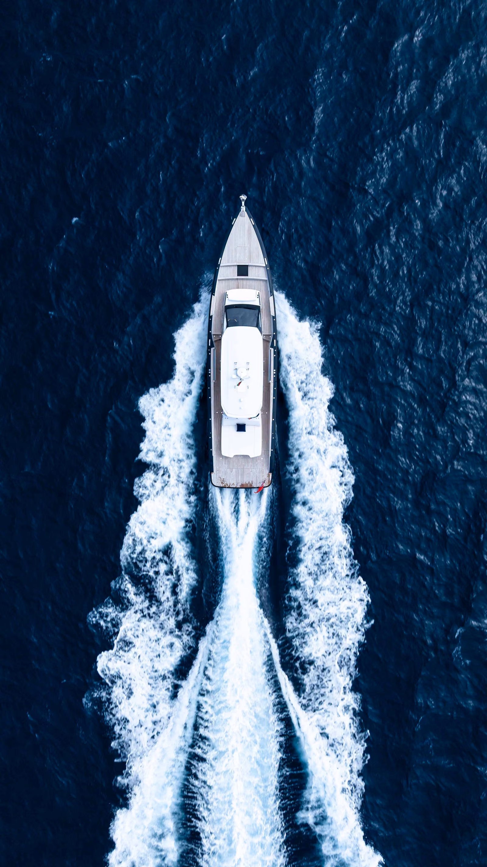 A tender carving a white wake across deep blue water, from above