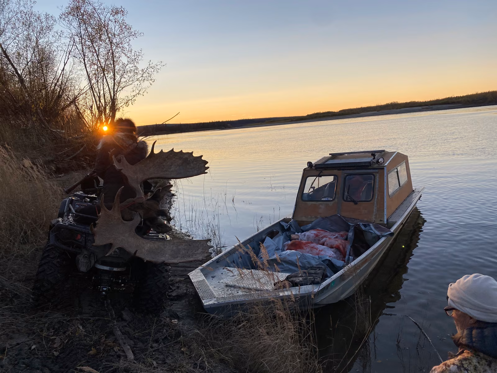 A skiff moored on the river at dusk below the spruce line